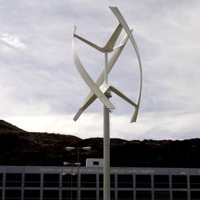 aerogenerador con élices dispuestas en diseño vertical. Atardecer. Al fondo cielo muy nuboso y ladera