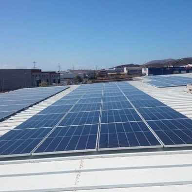 paneles solares sobre techo de nave industrial. Al fondo cielo azul despejado