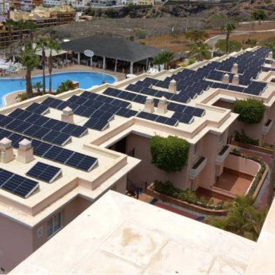 placas solares en techo de establecimiento hotelero. A la izquierda, parte de la piscina y palmeras