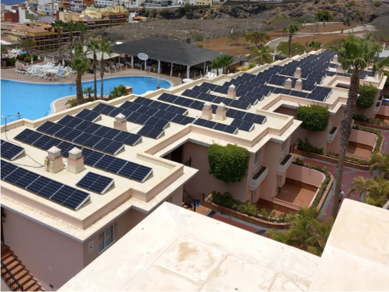placas solares en techo de establecimiento hotelero. A la izquierda, parte de la piscina y palmeras