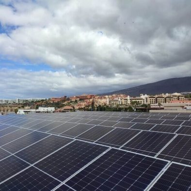 paneles solares en hotel. Cielo con nubes grises al fondo, junto a urbanización lejana