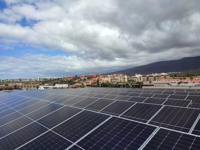 paneles solares en hotel. Cielo con nubes grises al fondo, junto a urbanización lejana