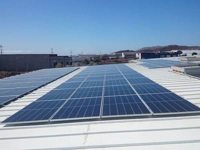 placas solares en techo de instalación industrial. Techo blanco. Al fondo cielo azul despejado